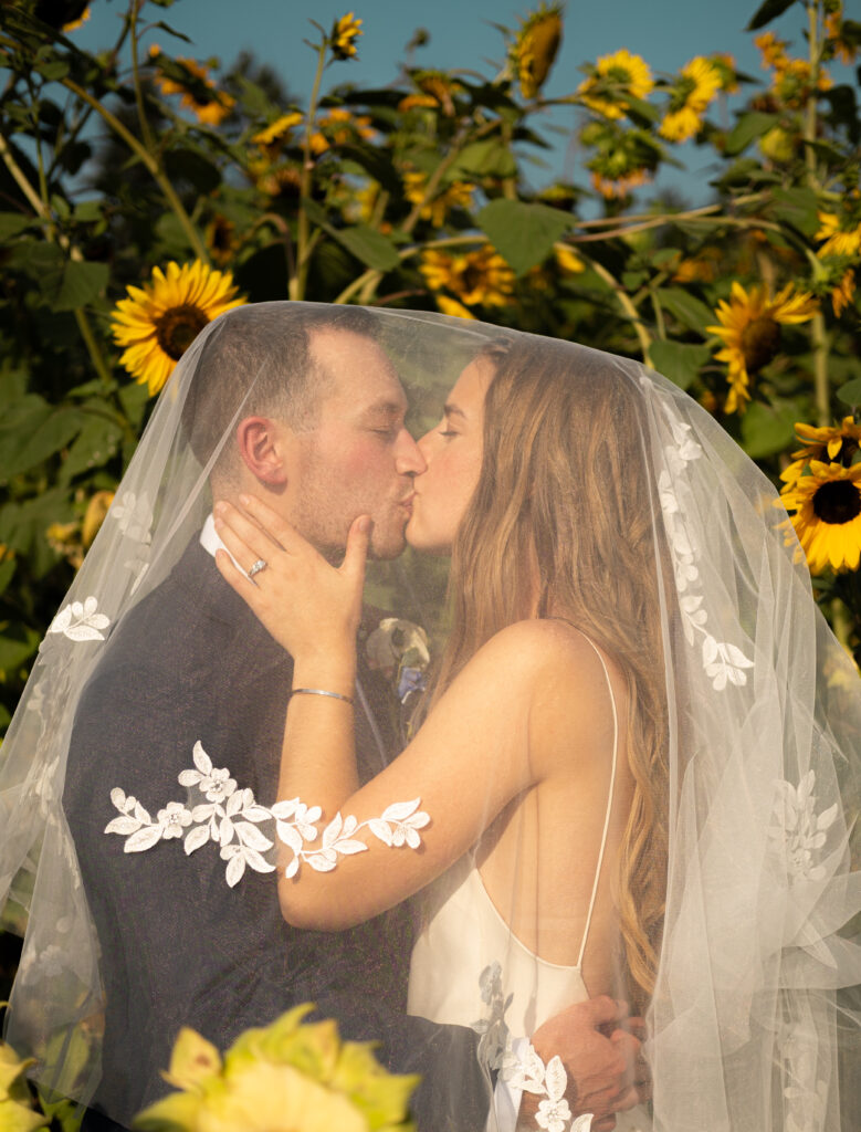 Portrait of a kiss under the veil in a sunflower garden